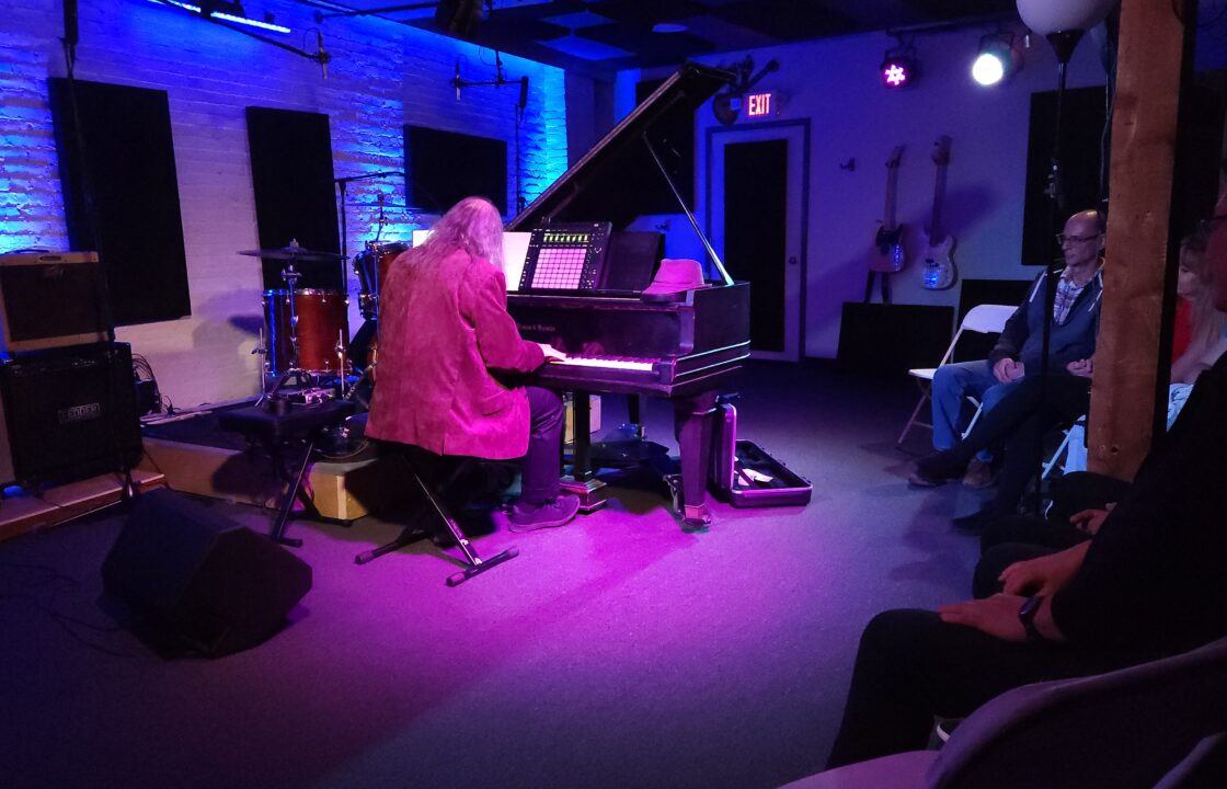 A piano player playing on our in house Mason & Hamlin Baby Grand with our blue and magenta stage lighting