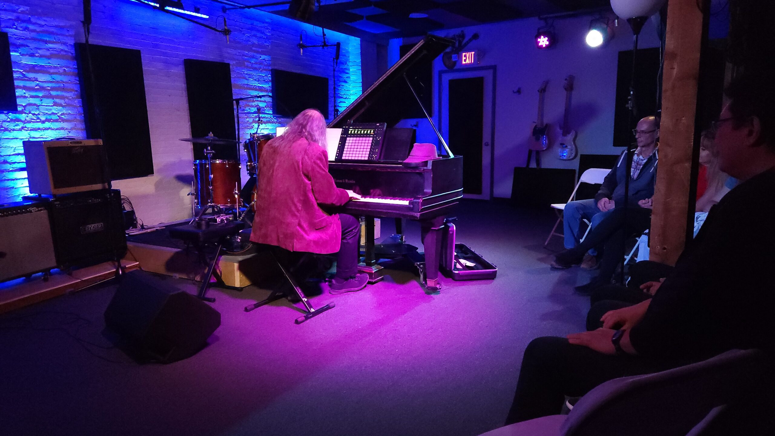 A piano player playing on our in house Mason & Hamlin Baby Grand with our blue and magenta stage lighting